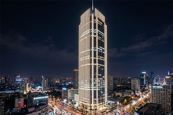 A towering skyscraper with long, unbroken vertical lines of 48V LED light.